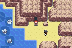 The player standing on a sandy coastal path between cliffs and water.